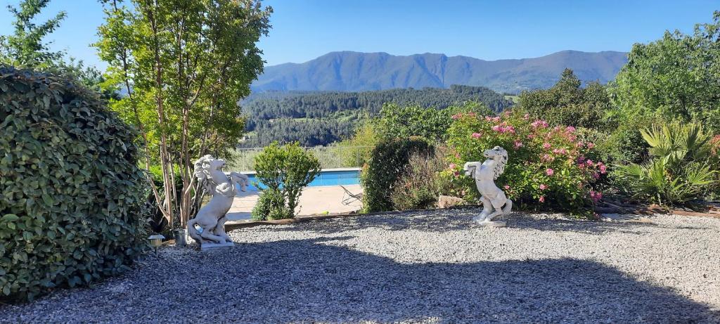 Deux statues de chats sont debout dans une cour dans l'établissement Maison avec piscine 10 personnes, à Chambajour