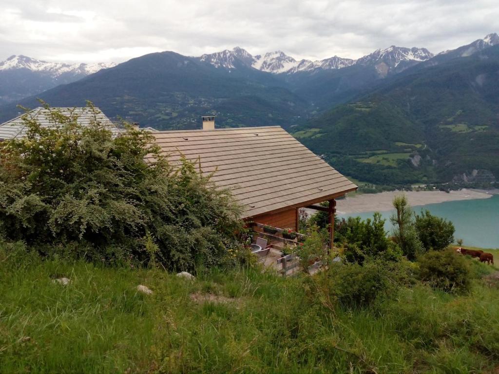 une maison sur le flanc d'une colline avec des montagnes dans l'établissement chalet à Puy Sanieres avec vue sur le lac de Serre Ponçon, à Puy-Sanières