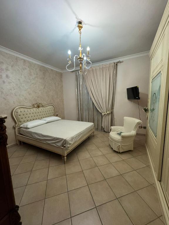 una camera con letto, lampadario a braccio e sedia di Valendriu's House a Torre Annunziata