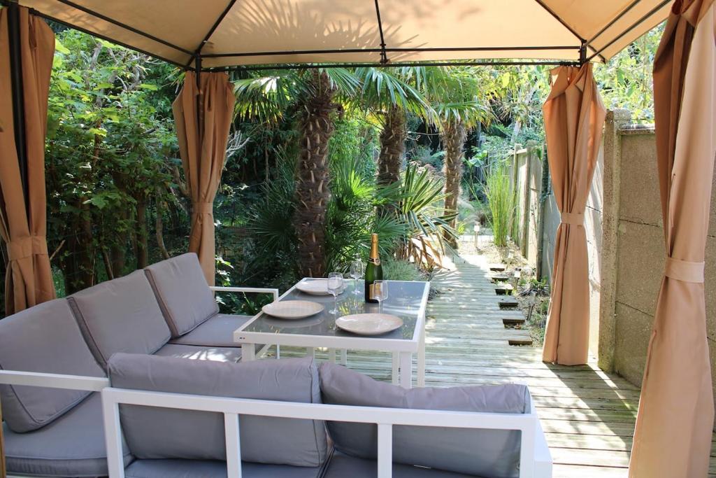 a patio with a couch and a table under a tent at Les Embruns in Neuville-lès-Dieppe