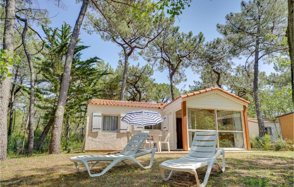 two chairs and an umbrella in front of a house at Lovely Home In La Faute-Sur-Mer in La Faute-sur-Mer