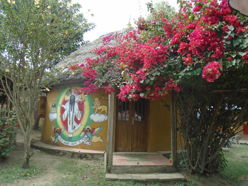 un petit bâtiment avec des fleurs roses devant lui dans l'établissement Zion Train Lodge Shashemene, à Kʼorē