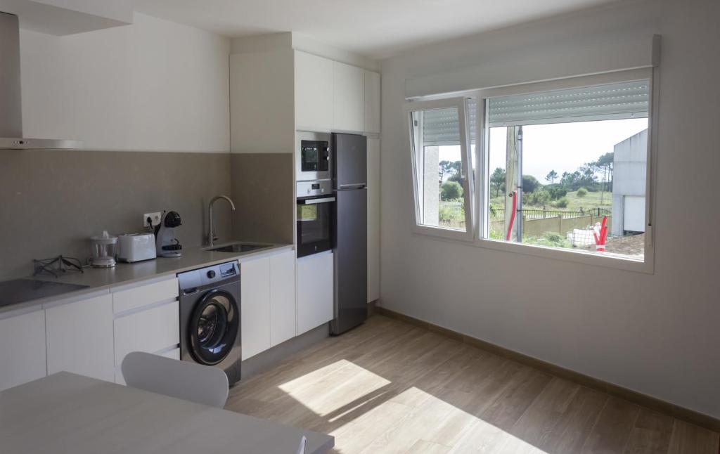 a kitchen with a washing machine and a window at Alén de Louro - Apartamento 3 Ancoradoiro in Gándara