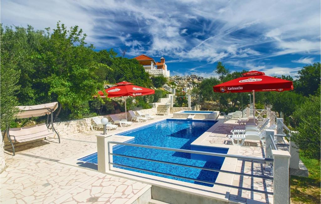 a swimming pool with umbrellas and chairs and a swimming pool at 10 Bedroom Beautiful Home In Kucice in Kučiće