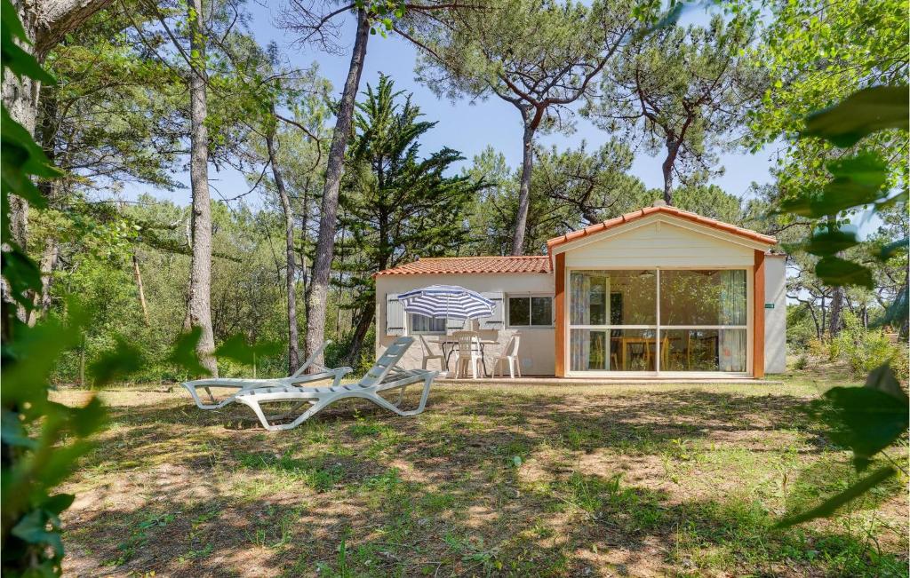 a cottage in the woods with a table and chairs at Awesome Home In La Faute Sur Mer in La Faute-sur-Mer