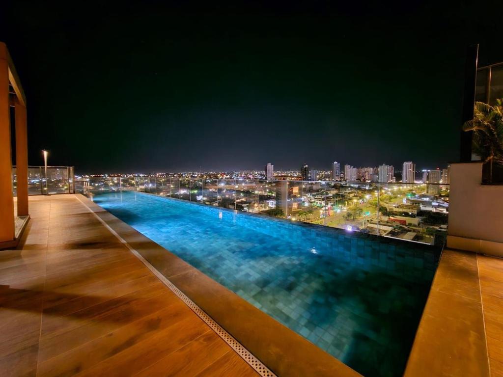 a pool on the roof of a building at night at Studio Bali, aconchego e luxo. in Campo Grande