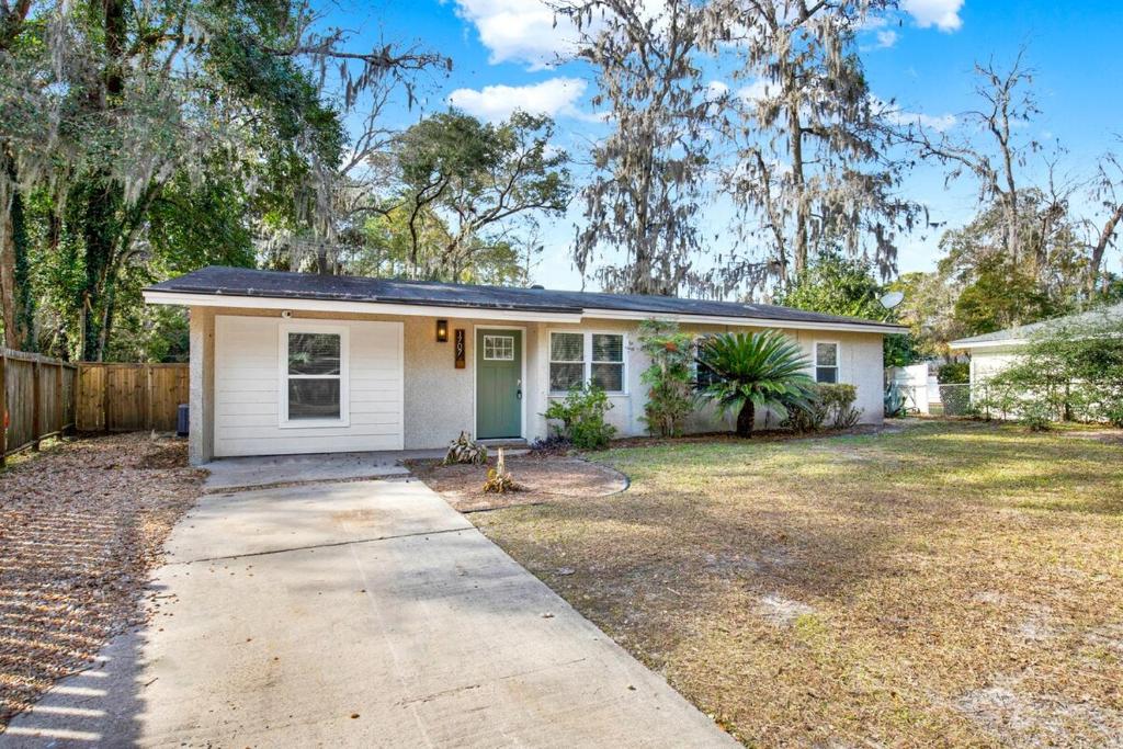Una pequeña casa blanca con entrada para coches. en Kings Way Bungalow, en Savannah