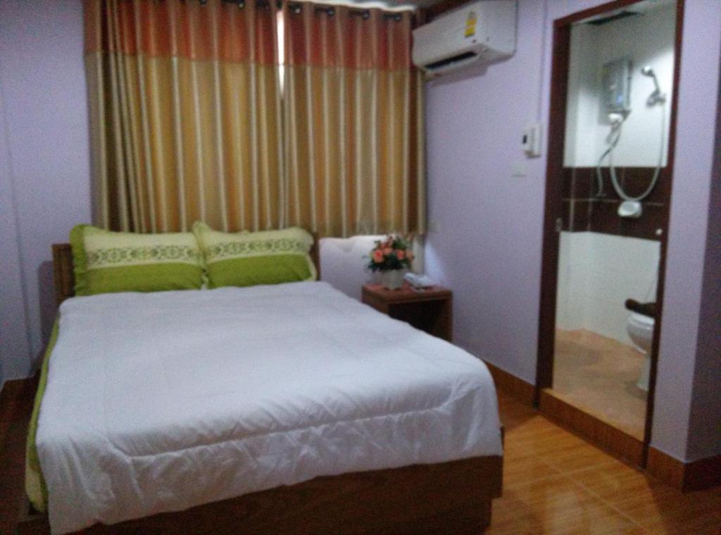 a bedroom with a bed and a bathroom with a window at Phoonsab Hostel in Phitsanulok