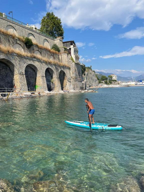 a man standing on a paddle board in the water at B&B DieMme Amalfi Coast in Vietri sul Mare
