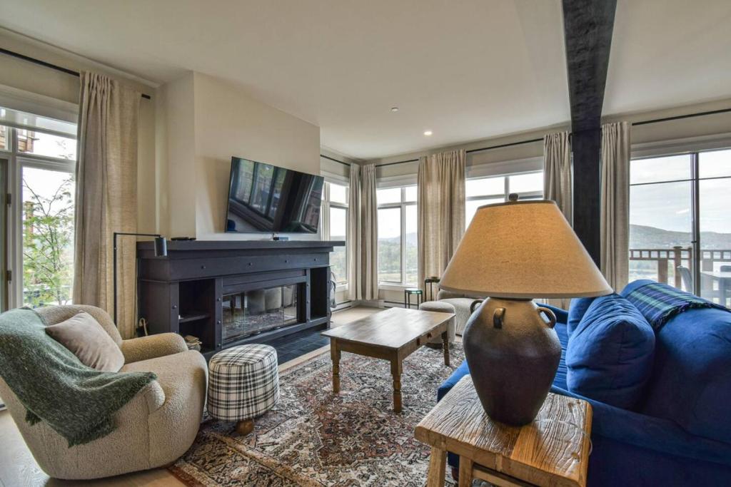 Una sala de estar con un sofá azul y una chimenea. en Altitude 170-8 Ultimate Luxury, en Mont-Tremblant