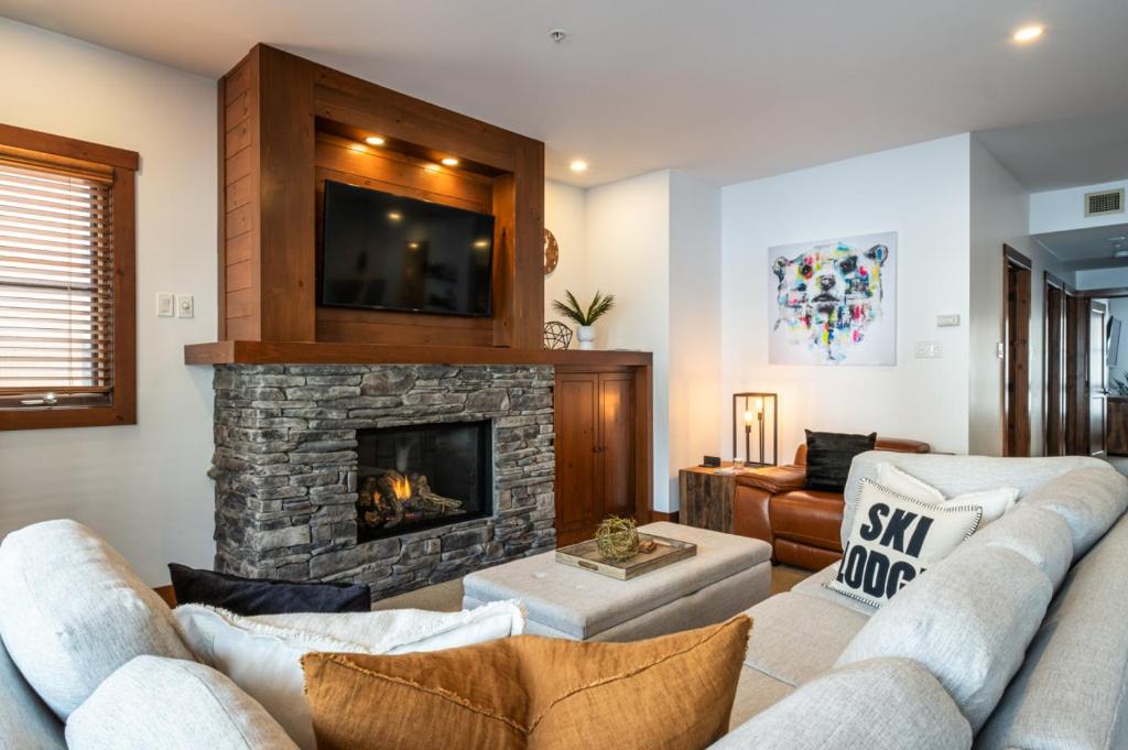 Una sala de estar con un sofá y una chimenea. en Spacious condo on the SLOPES - ETOILE 1510-4, en Mont-Tremblant