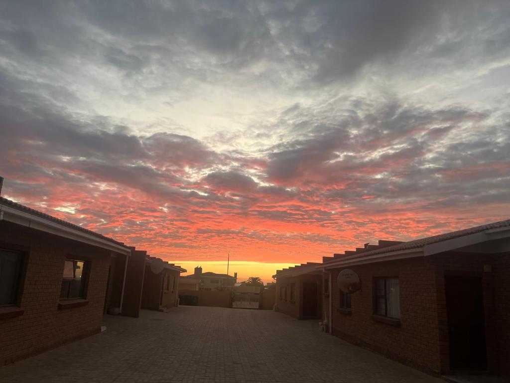 a sunset in the sky over a street with buildings at Paresis 7 in Hentiesbaai
