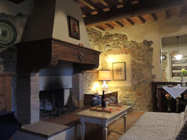 カステッリーナ・イン・キアンティにあるIl Rusticoの石造りの暖炉とテーブル付きのリビングルーム