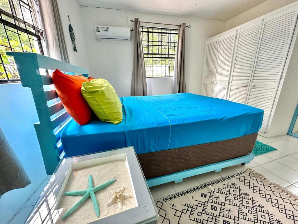 a bedroom with a blue bed with two colorful pillows at South Coast - Private in Christ Church