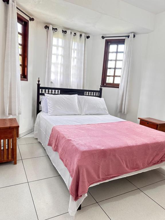 a bedroom with a large bed with a pink blanket at Casa linda e aconchegante in Gravatá