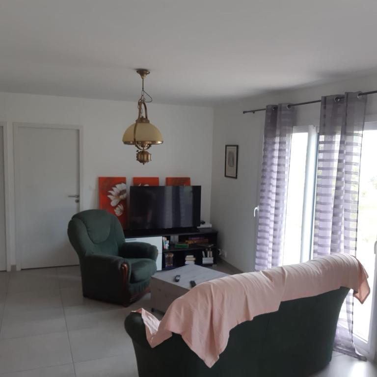 - un salon avec un canapé, une chaise et une télévision dans l'établissement La route des Genêts, à Locronan