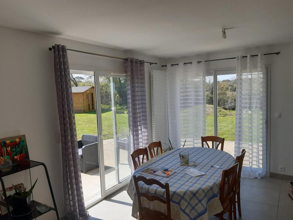 a dining room with a table and chairs and sliding glass doors at La route des Genêts in Locronan