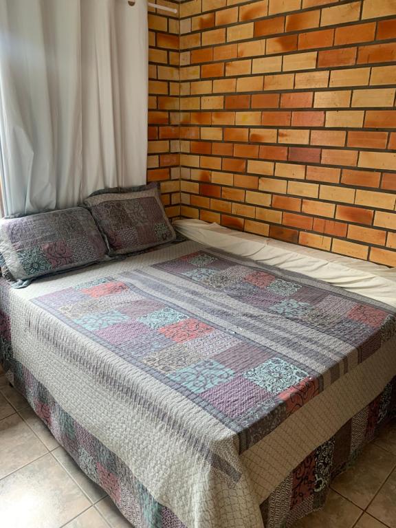 Posto letto in camera con muro di mattoni di Casa família com piscina a Garopaba