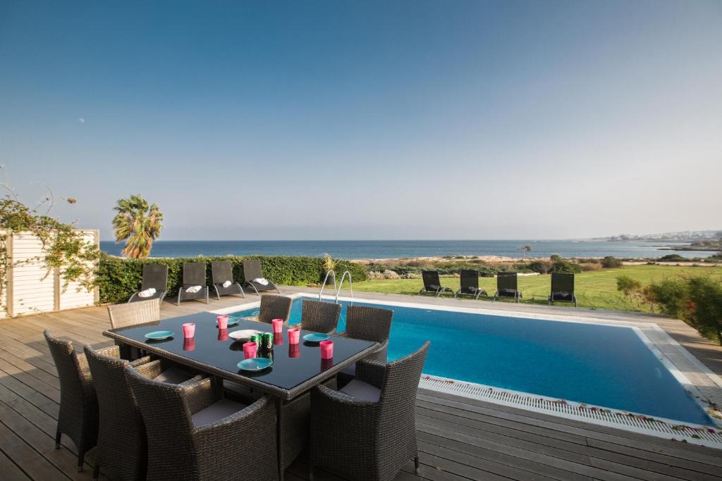 a patio with a table and chairs next to a swimming pool at Leana Front Line Villa in Protaras