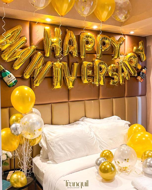 a bed with gold balloons and a happy new year sign at Azure Staycation in Manila