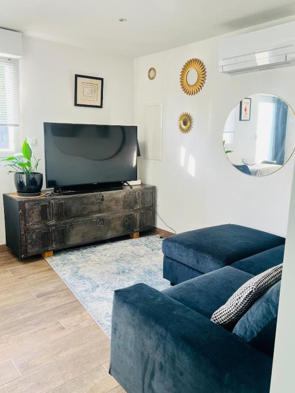 - un salon avec une télévision et un canapé bleu dans l'établissement Petite maison indépendante proche Strasbourg, à Brumath