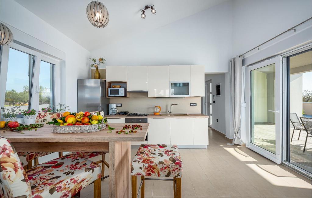kuchnia ze stołem, na którym stoi miska z owocami w obiekcie Awesome Home In Vodnjan w mieście Vodnjan