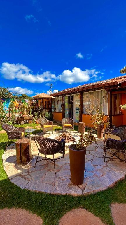 Un patio con sillas y mesas y un edificio. en Pousada Lua Clara, en Alto Paraíso de Goiás