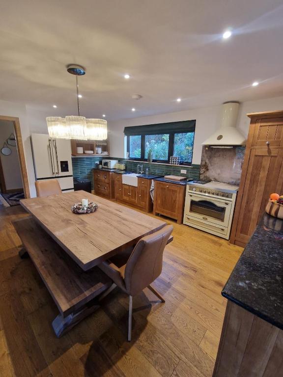 a large kitchen with a wooden table and a kitchen with a stove at Cedar Lodge in Bowness-on-Windermere