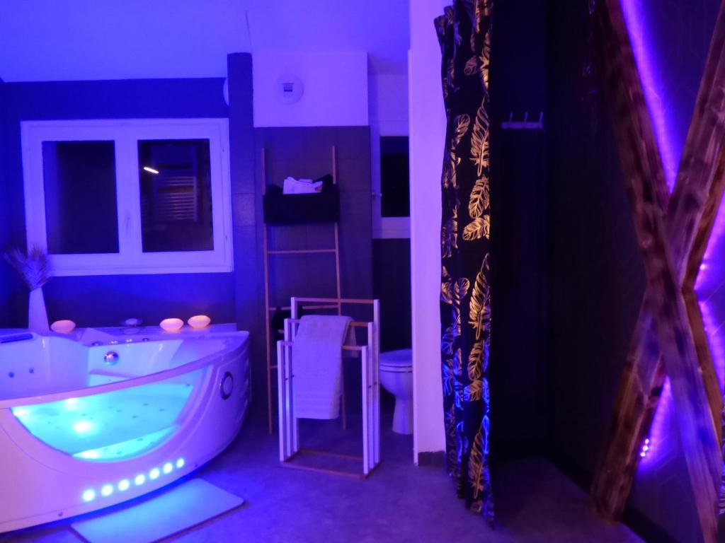 - une salle de bains avec baignoire dans une chambre violette dans l'établissement L'Instant pour Soi, à Saint-Gervais-les-Trois-Clochers