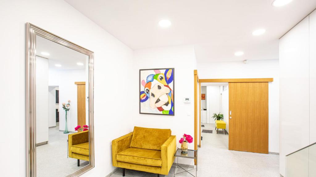 un miroir dans un couloir avec une chaise jaune dans l'établissement The Royal Goat Near Castle and Presidential Palace, à Bratislava