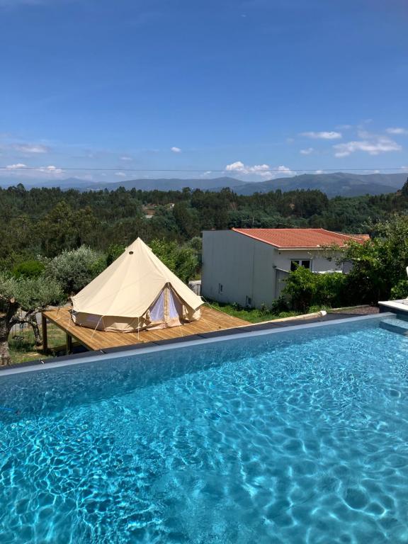 a tent and a swimming pool next to a building at Vale Coelhos Casa de Campo in Sarnadela