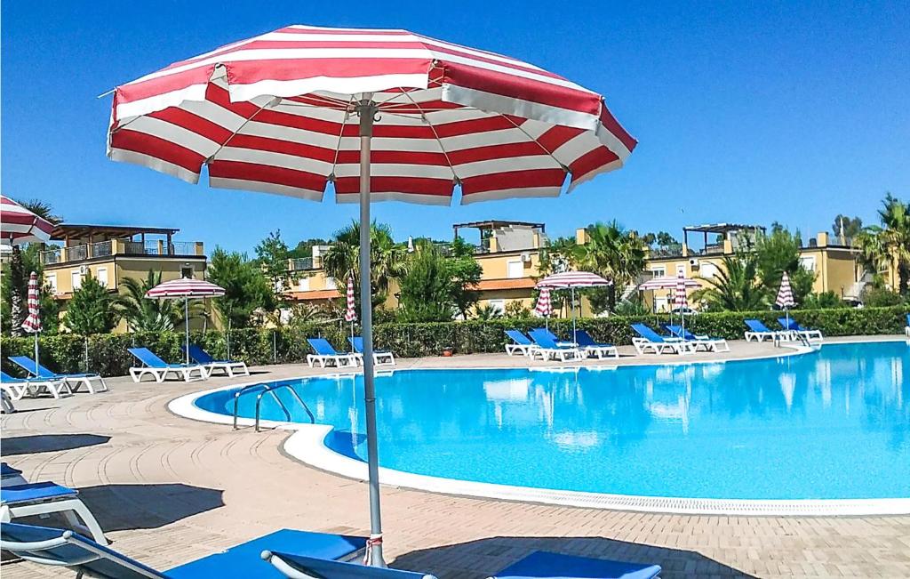a pool with a red and white umbrella and chairs at Casa 79 G in Pizzo