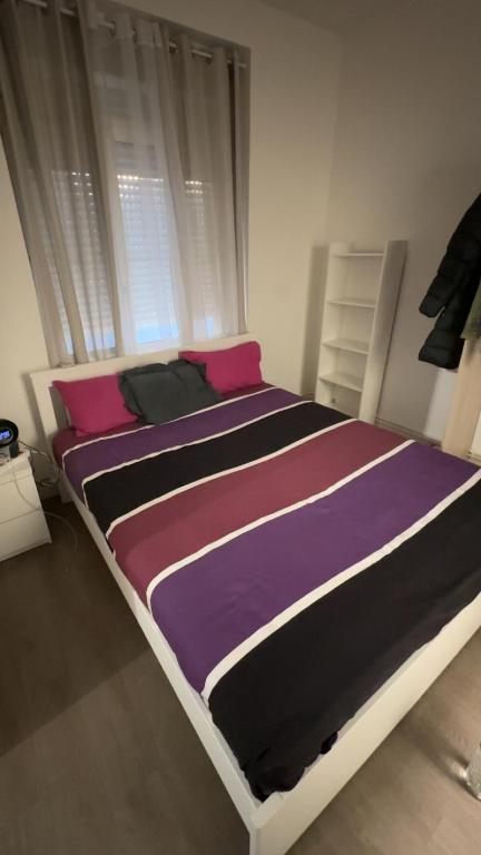 - un lit avec des draps violets et roses dans une chambre dans l'établissement Apparemment T1 cosy, à Cabriès