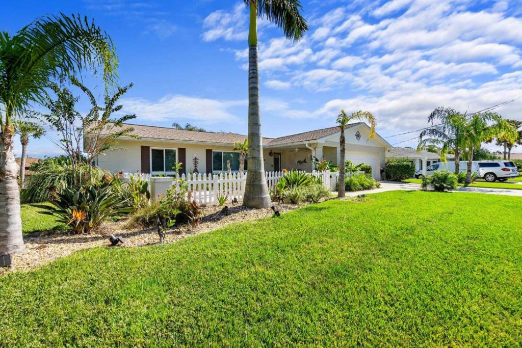 a house with palm trees and a white fence at Dockside Serenity in Palm Coast