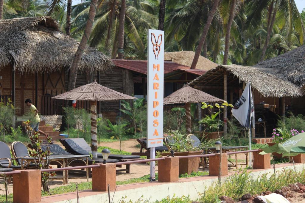 ein Schild vor einem Resort mit Stühlen und Sonnenschirmen in der Unterkunft Mariposa Beach Grove in Agonda