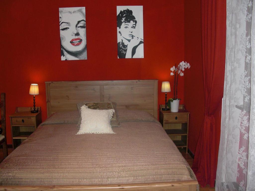 a bedroom with a bed with red walls and posters at La Maison Blanche in Borghesiana 