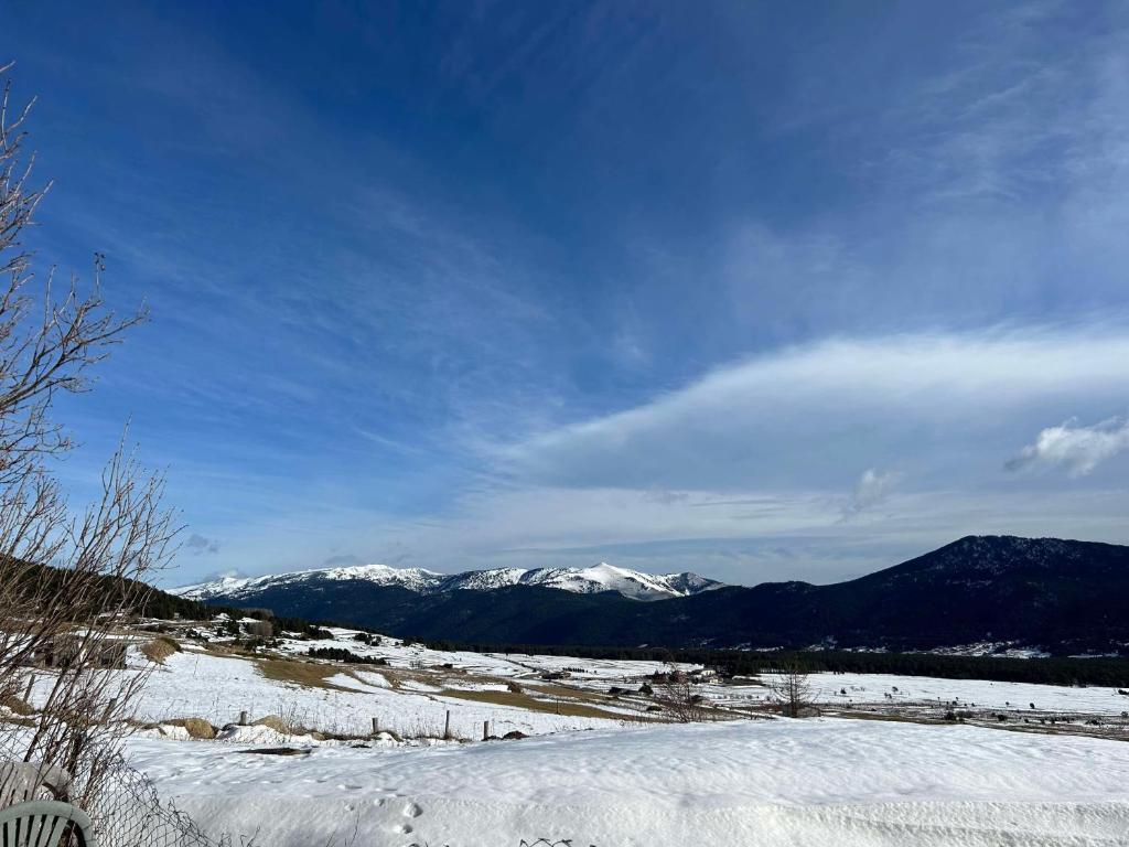 un champ enneigé avec des montagnes en arrière-plan dans l'établissement Appartement Cosy avec jardin, aux Angles