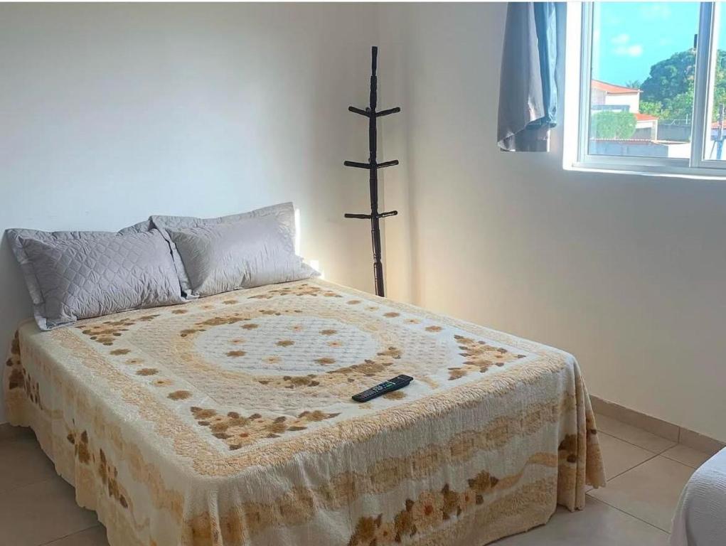 a bed in a white room with a cross at Flat - Jacumã - Conde in Conde