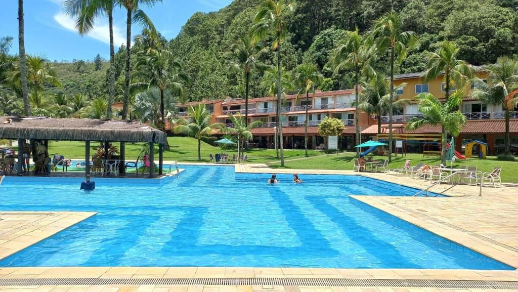 una grande piscina in un resort con palme di Casa inteira na PRAIA & SERRA Melhor Resort Angra a Conquista