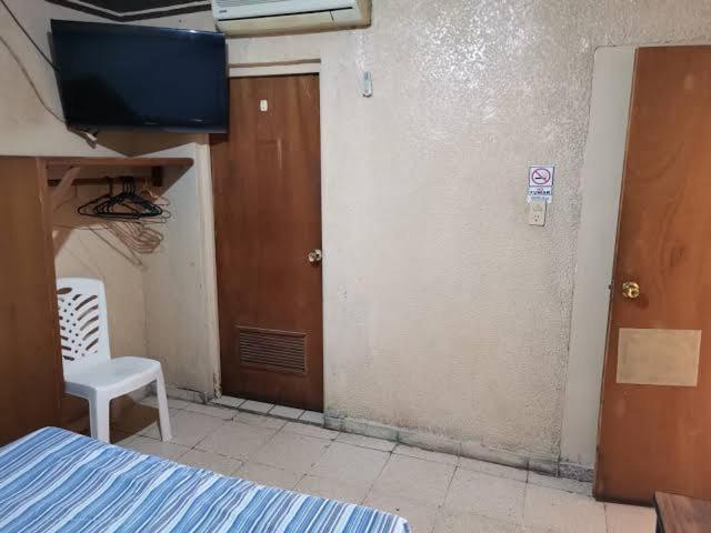 ein Zimmer mit einem Bett, einer Tür und einem Stuhl in der Unterkunft Departamento Doki in Hermosillo