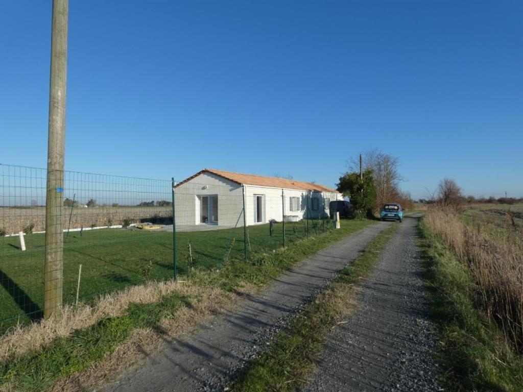 un chemin de terre à côté d'une maison et d'une clôture dans l'établissement Maison 94m² rénovée, 4 personnes, animaux admis, jardin - FR-1-540-311, à Notre-Dame-de-Monts