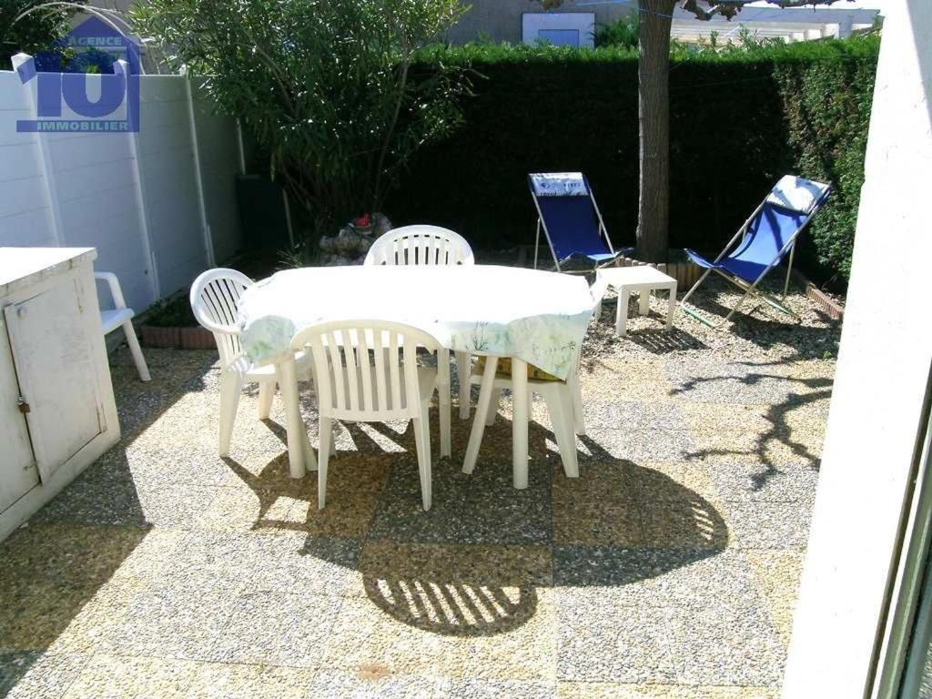 une table blanche et des chaises sur une terrasse dans l'établissement Charmant pavillon avec piscine et parking, proche plage - FR-1-781-83, à Valras-Plage