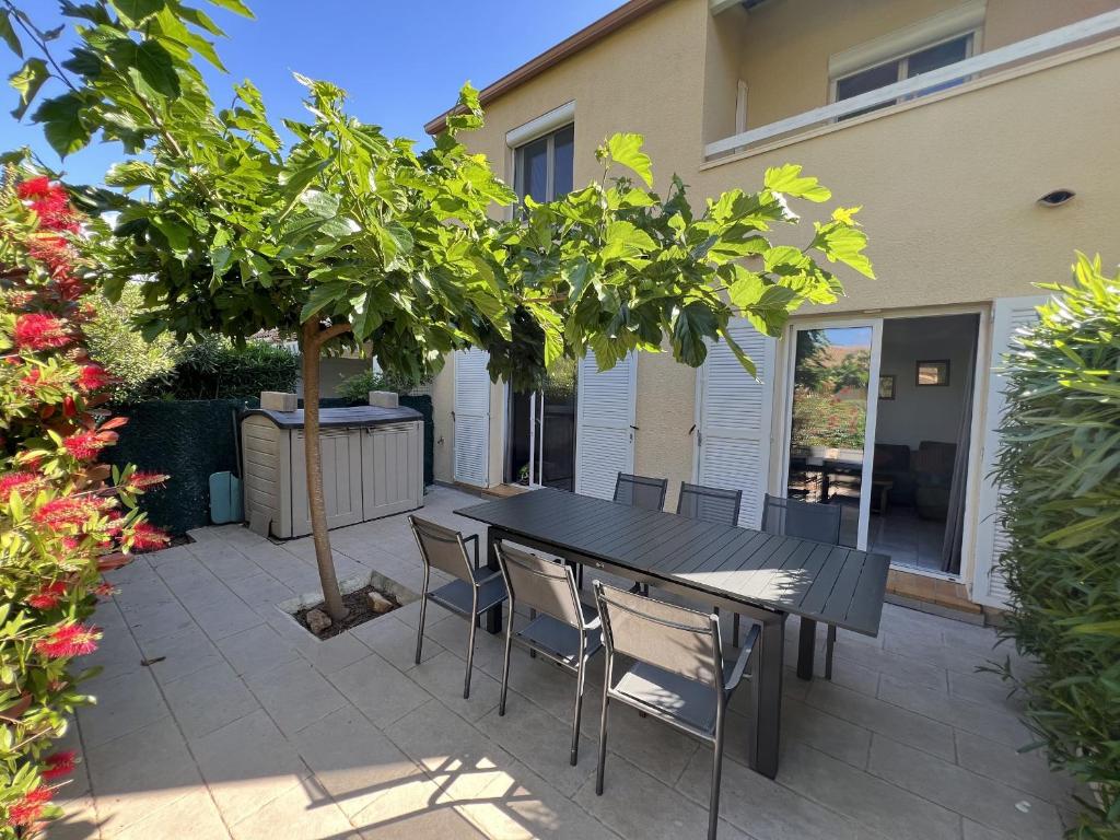 une table noire et des chaises sous un arbre sur une terrasse dans l'établissement Villa 8 Pers avec Garage et Piscine à 450m de la Plage - FR-1-781-84, à Valras-Plage