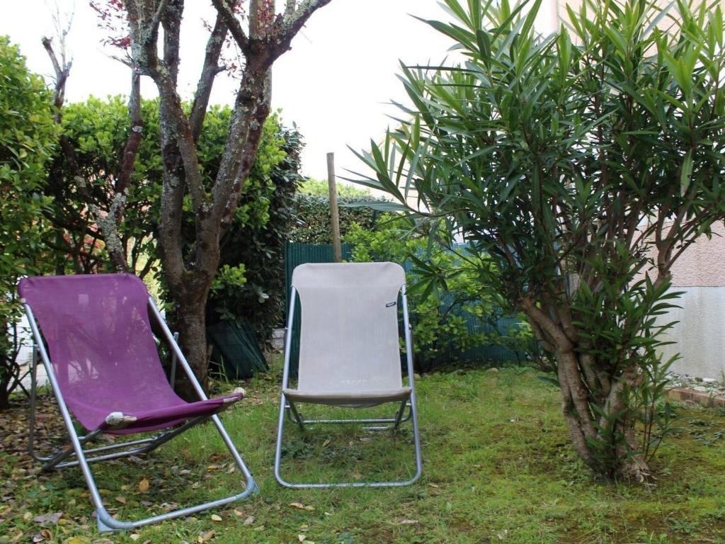 deux chaises assises dans l'herbe à côté d'un arbre dans l'établissement Maison 5 pers. proche plage avec jardin, parking - FR-1-246A-333, à Dolus-d'Oléron