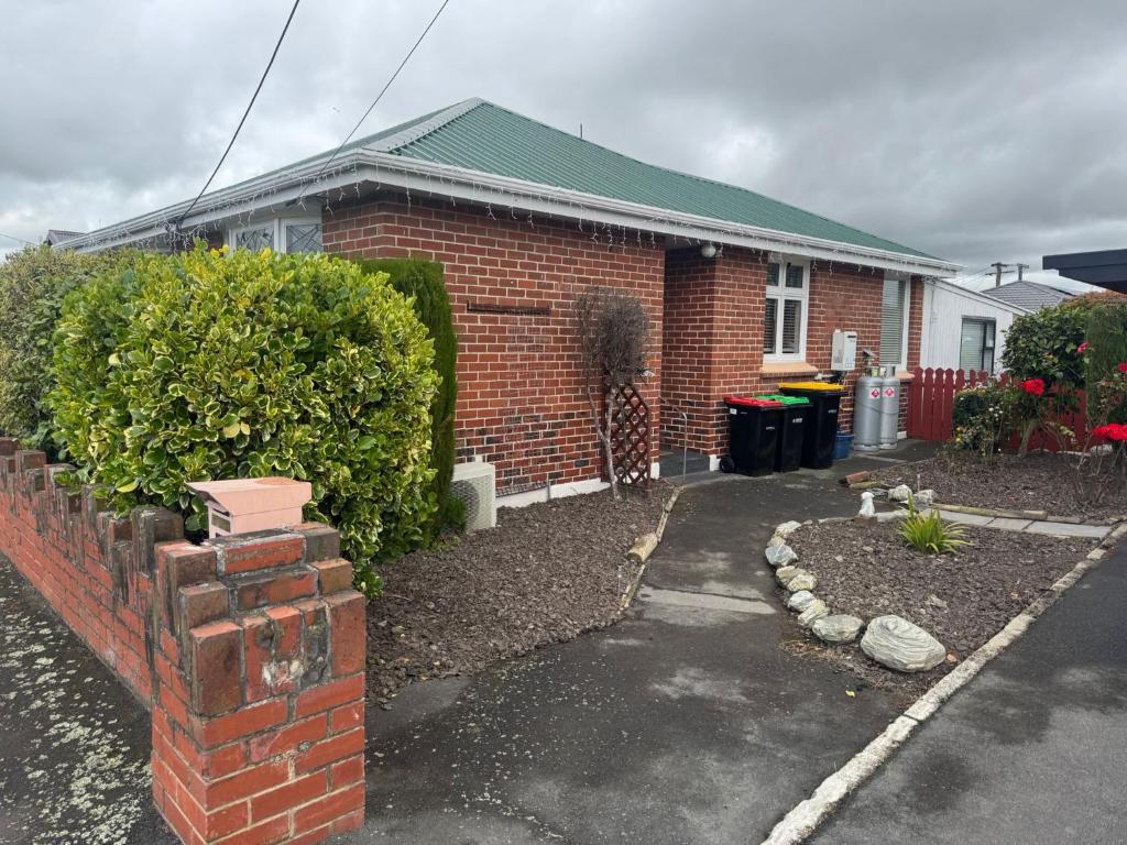 a house with a brick wall and a driveway at Relax In Mosgiel in Mosgiel