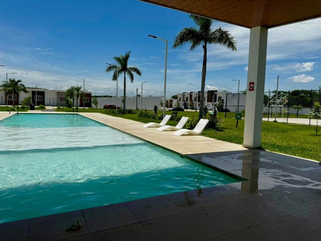una piscina con sillas y palmeras en Casa Bonita, en San Miguel