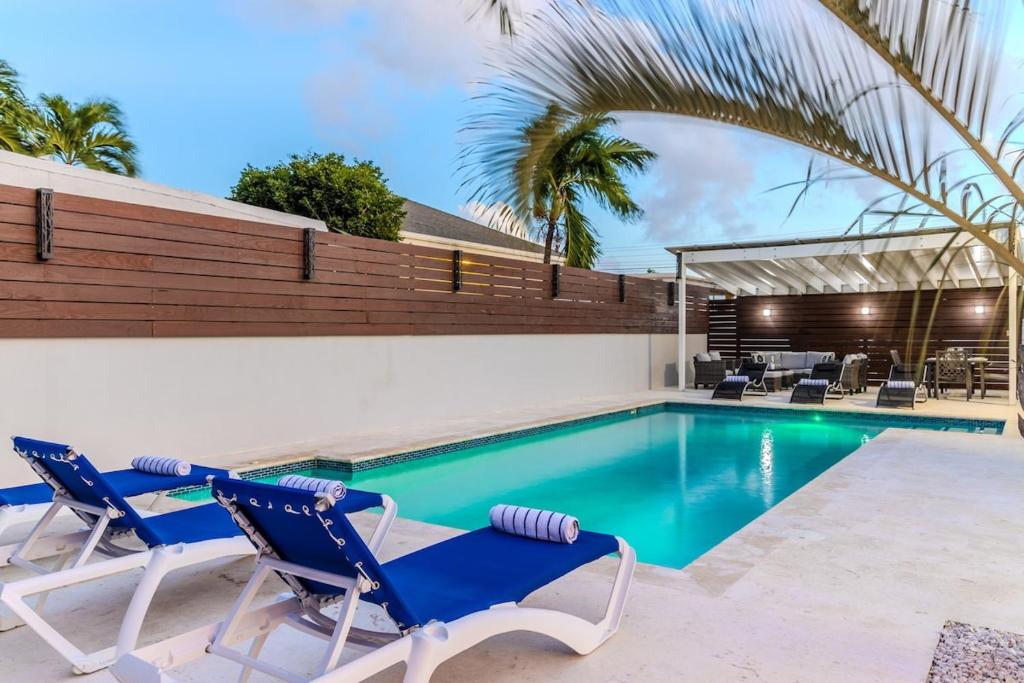 a swimming pool with two blue chairs and a table at 5 minutes to Eagle Beach Blue Lagoon by Bocobay in Palm-Eagle Beach