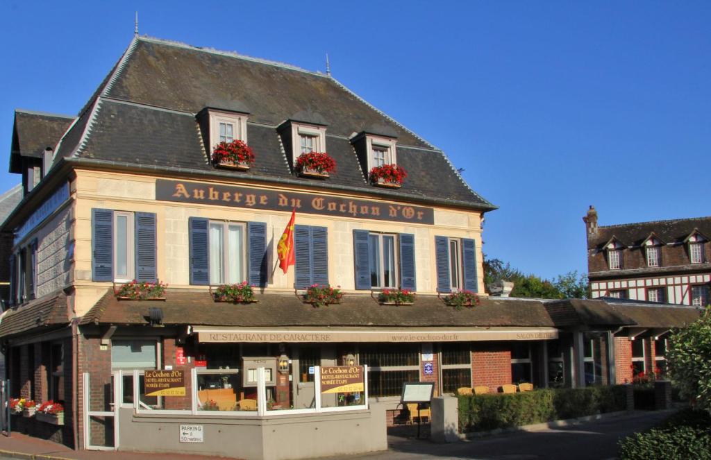 un edificio de madera de color rojo con una bandera en él en L'auberge Du Cochon D'or, en Beuzeville