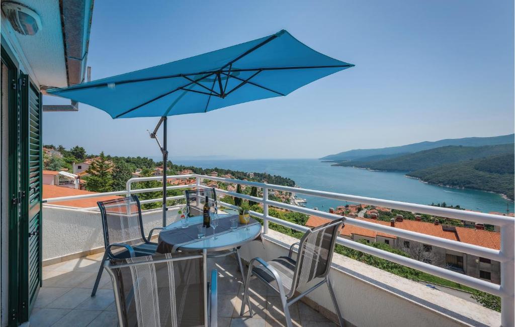 a blue table with chairs and an umbrella on a balcony at Amazing Apartment In Rabac With Kitchen in Rabac
