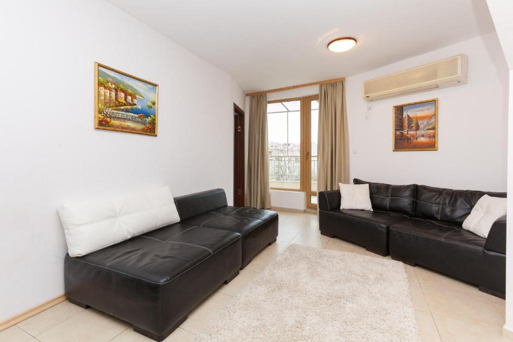 a living room with a black leather couch at Apartment Lermontov in Burgas City